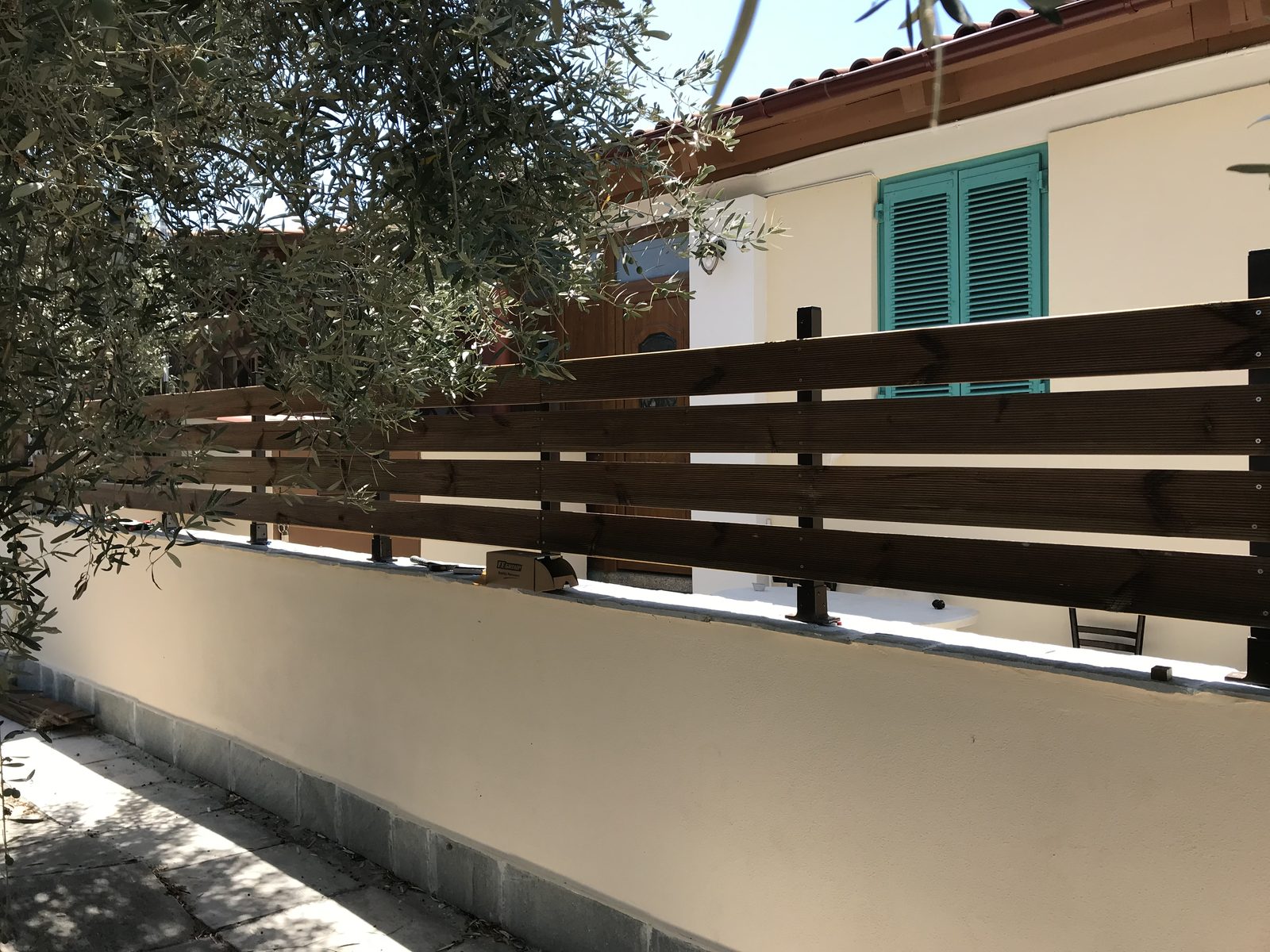 Οριζόντιες τάβλες από σουηδικό ξύλο εμποτισμού σε μεταλλικό σκελετό, πάνω σε μαντρότοιχο αυλής