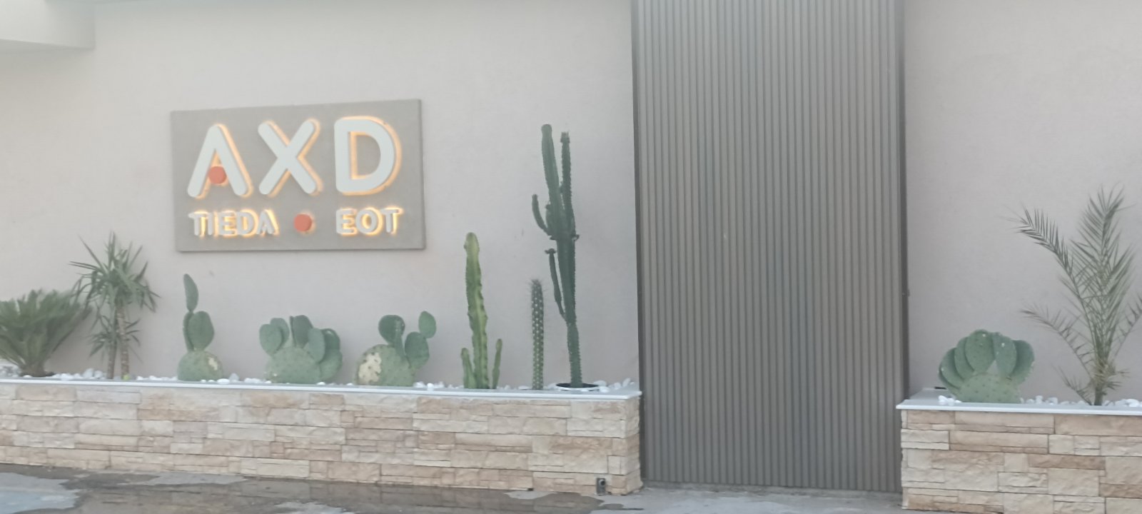 Πόρτα με 3D πηχάκι σε γκρι απόχρωση, στην πρόσοψη επαγγελματικού χώρου με ζαρντινιέρες