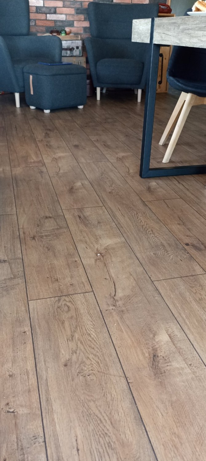 Δάπεδο laminate σε απόχρωση δρυς, σε καθιστικό με πολυθρόνες και τραπεζαρία